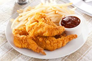 Plate of fried chicken tenders with side of fries and ketchup