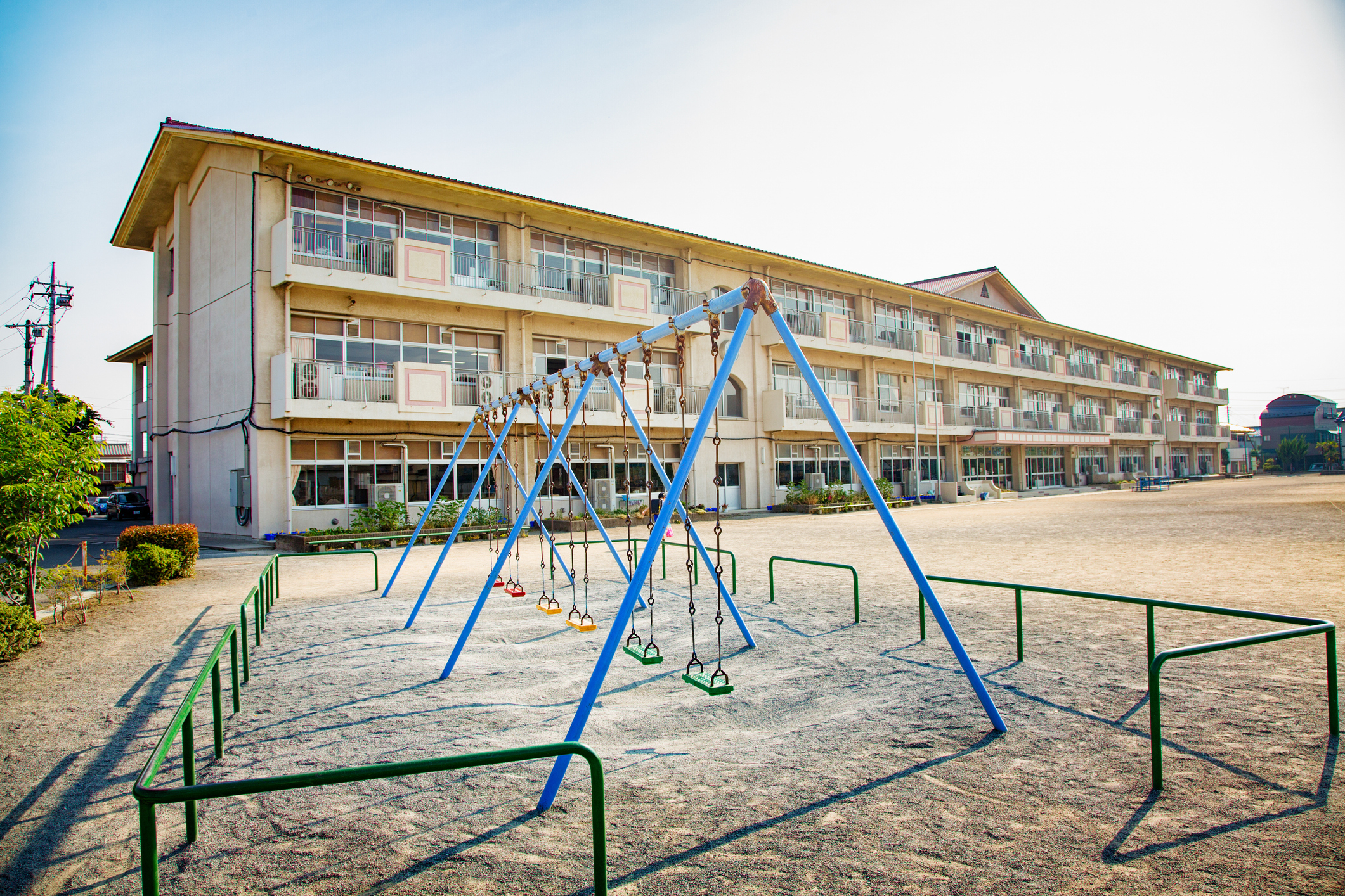 Playground with a swing and climbing structure in front of a multi-story motel during daytime