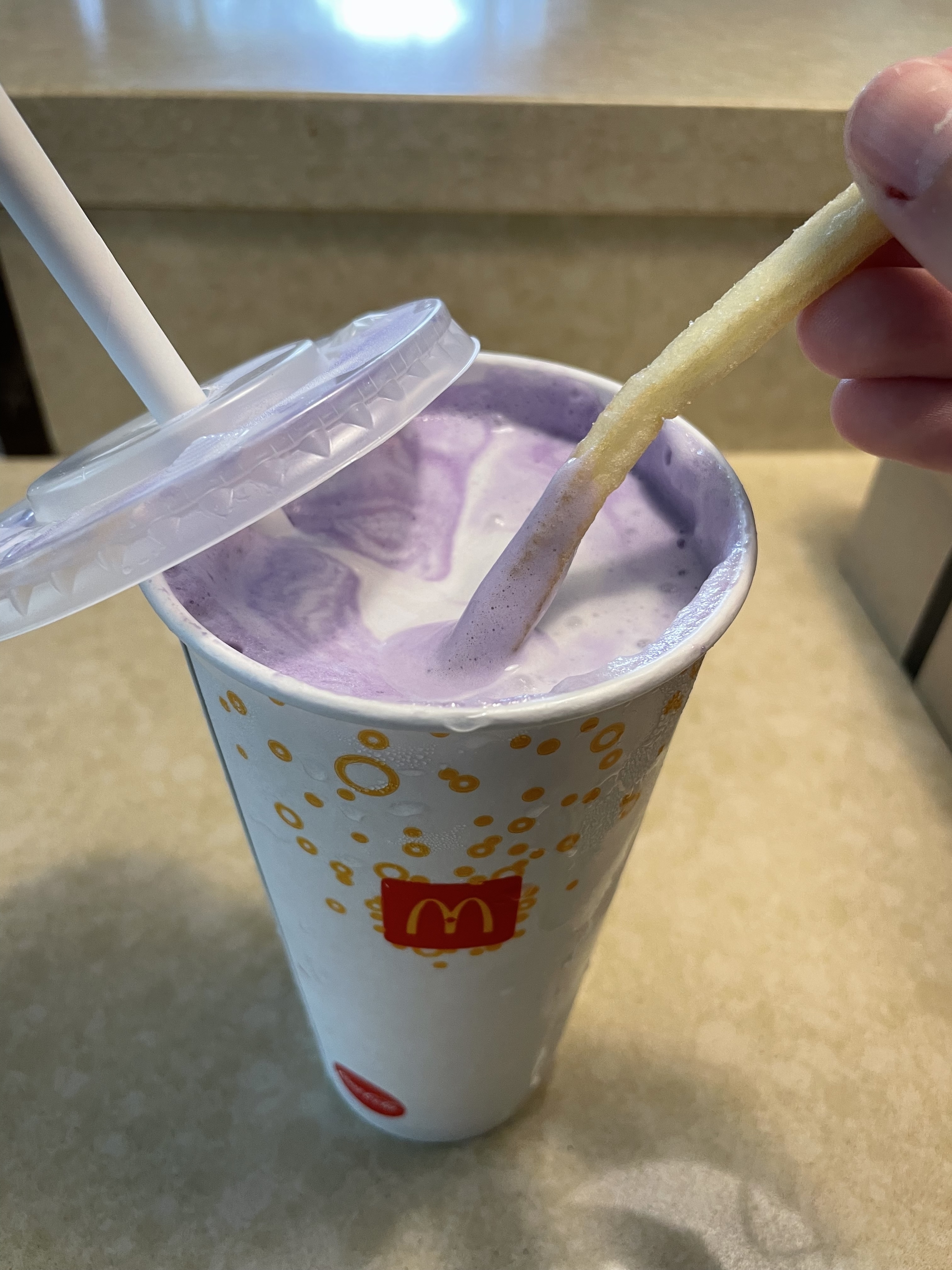 Hand dipping a French fry into a McDonald's milkshake