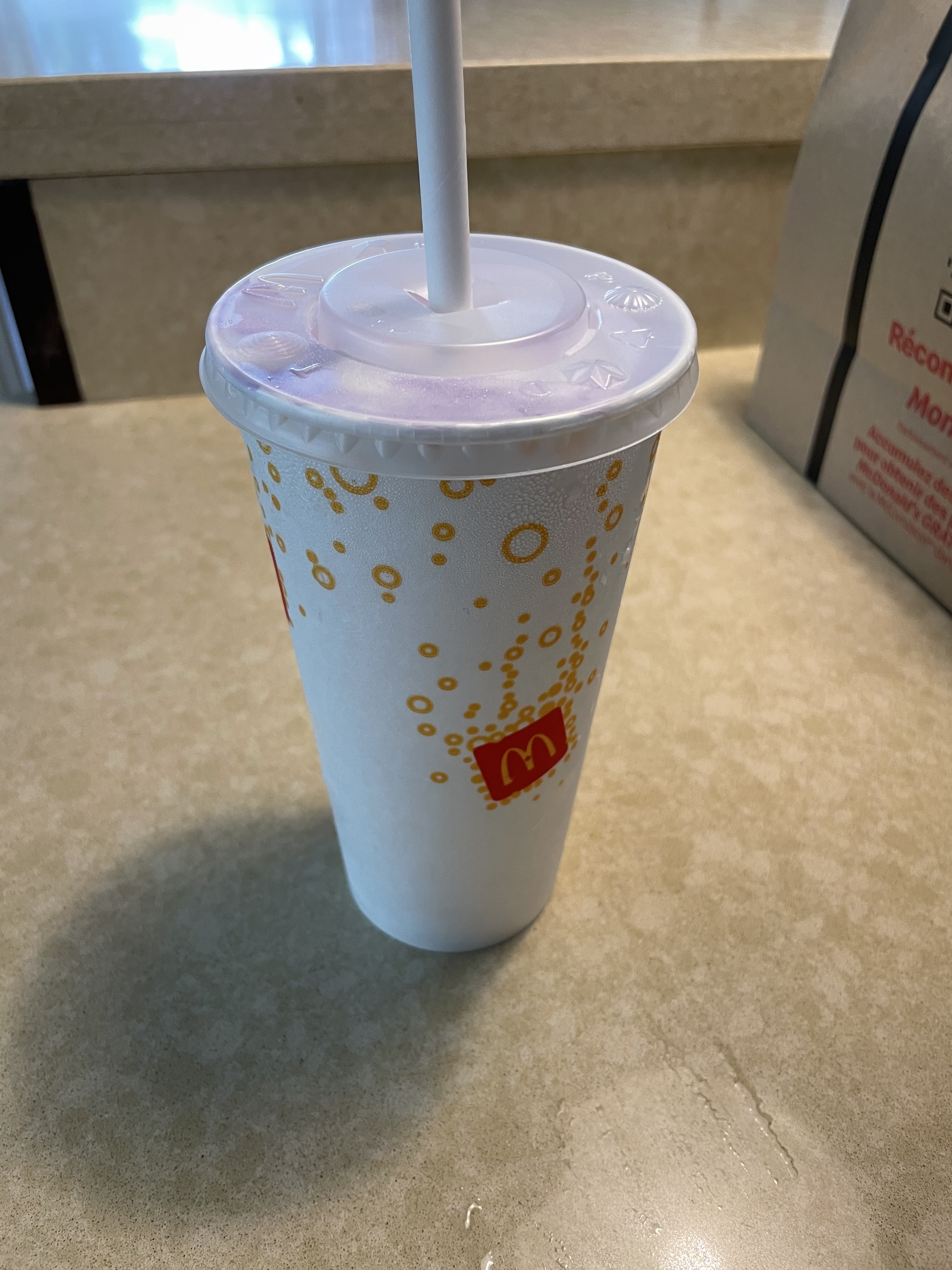 A McDonald's soda cup with a straw on a counter