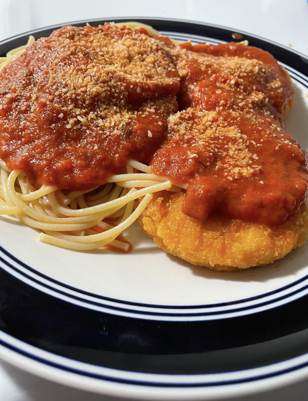 Plate with spaghetti, tomato sauce, breaded cutlets, and grated cheese