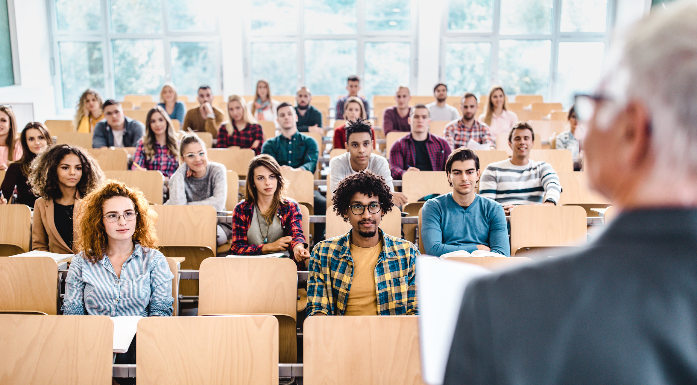 A diverse group of students attentively listening to a lecturer in a university classroom