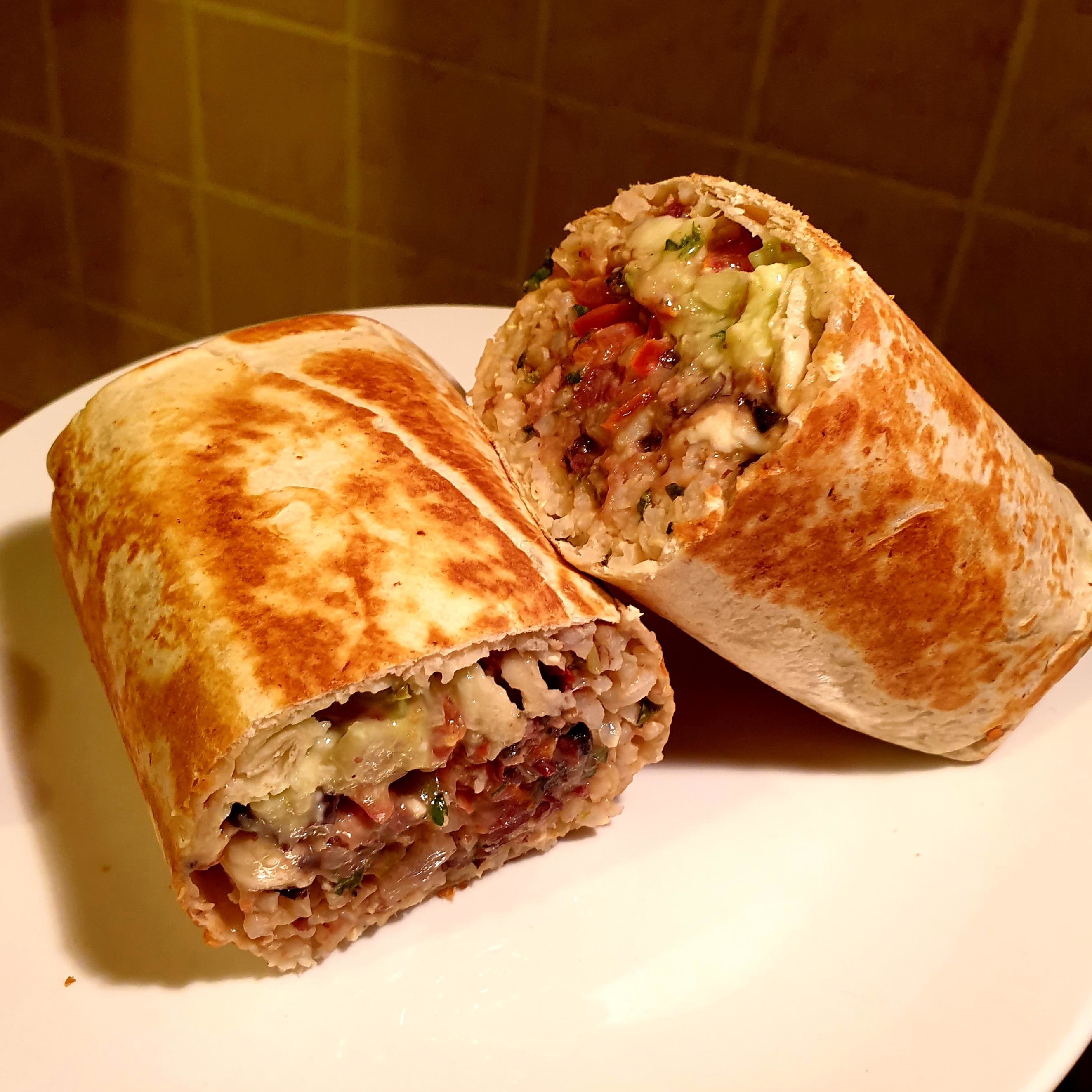 A burrito cut in half, revealing rice, beans, and avocado