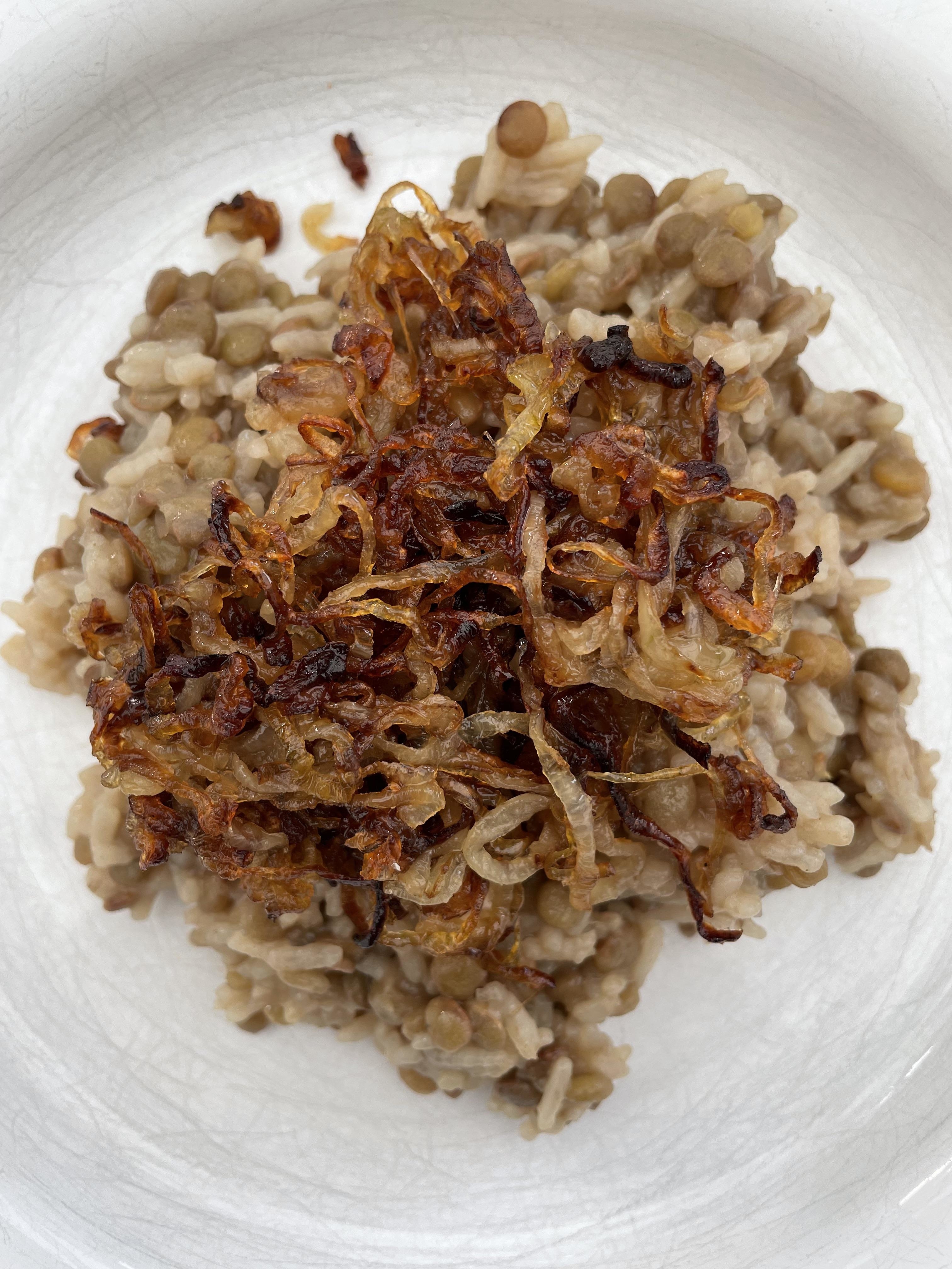 A plate of cooked grains topped with crispy fried onions