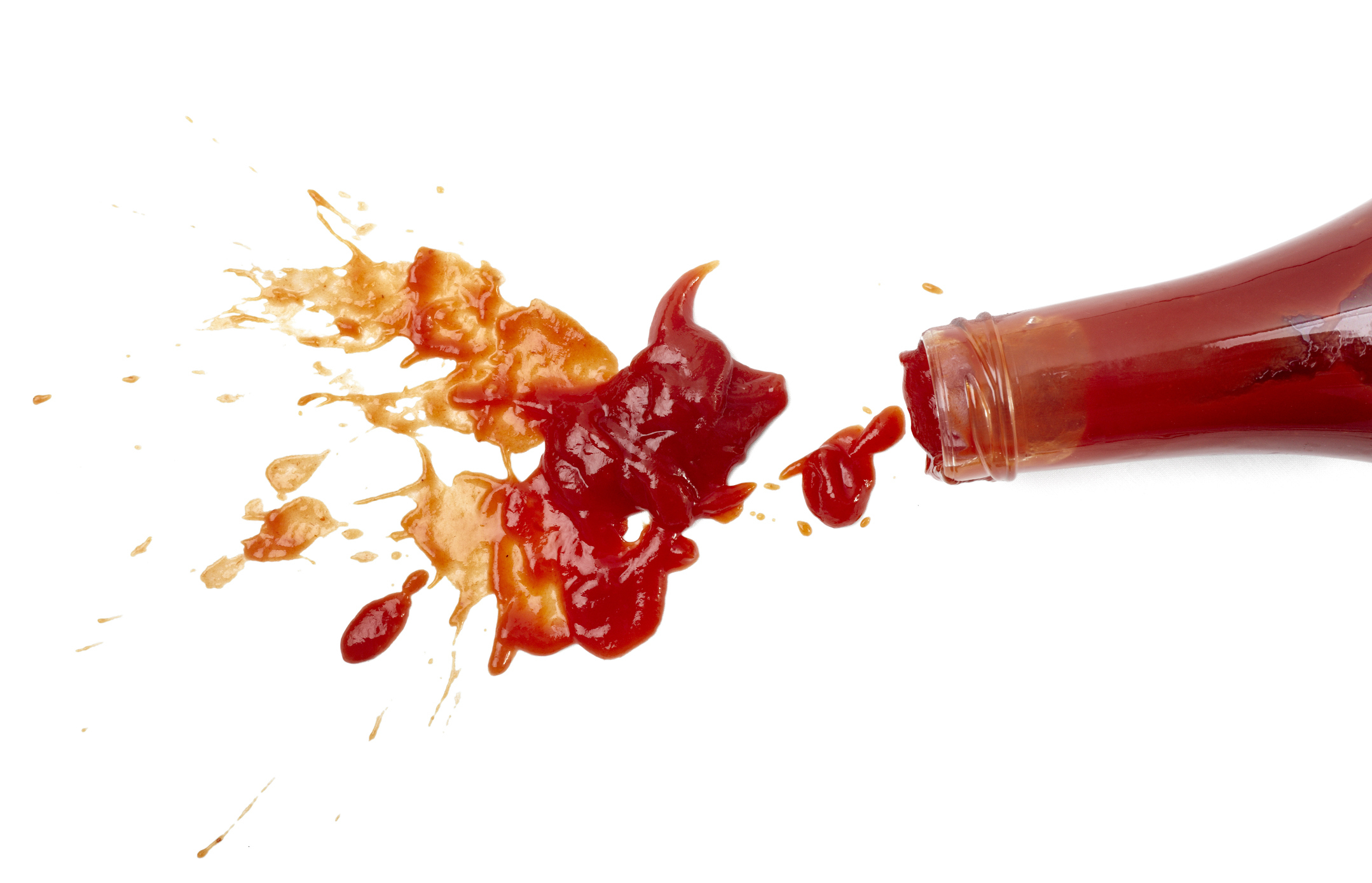 Overturned ketchup bottle with sauce spilling out onto a white surface