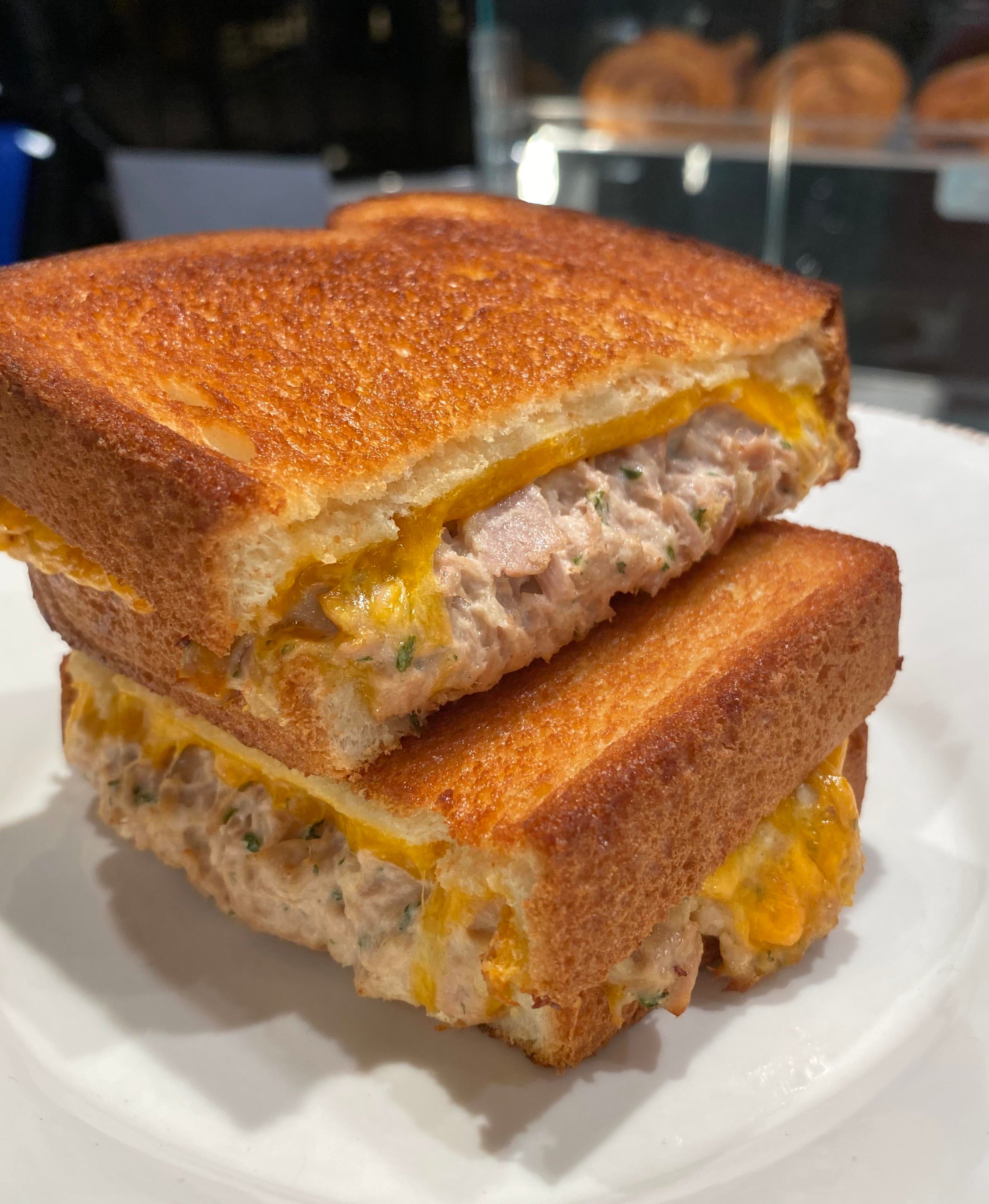 A tuna melt sandwich on a plate with a crispy crust and melted cheese visible