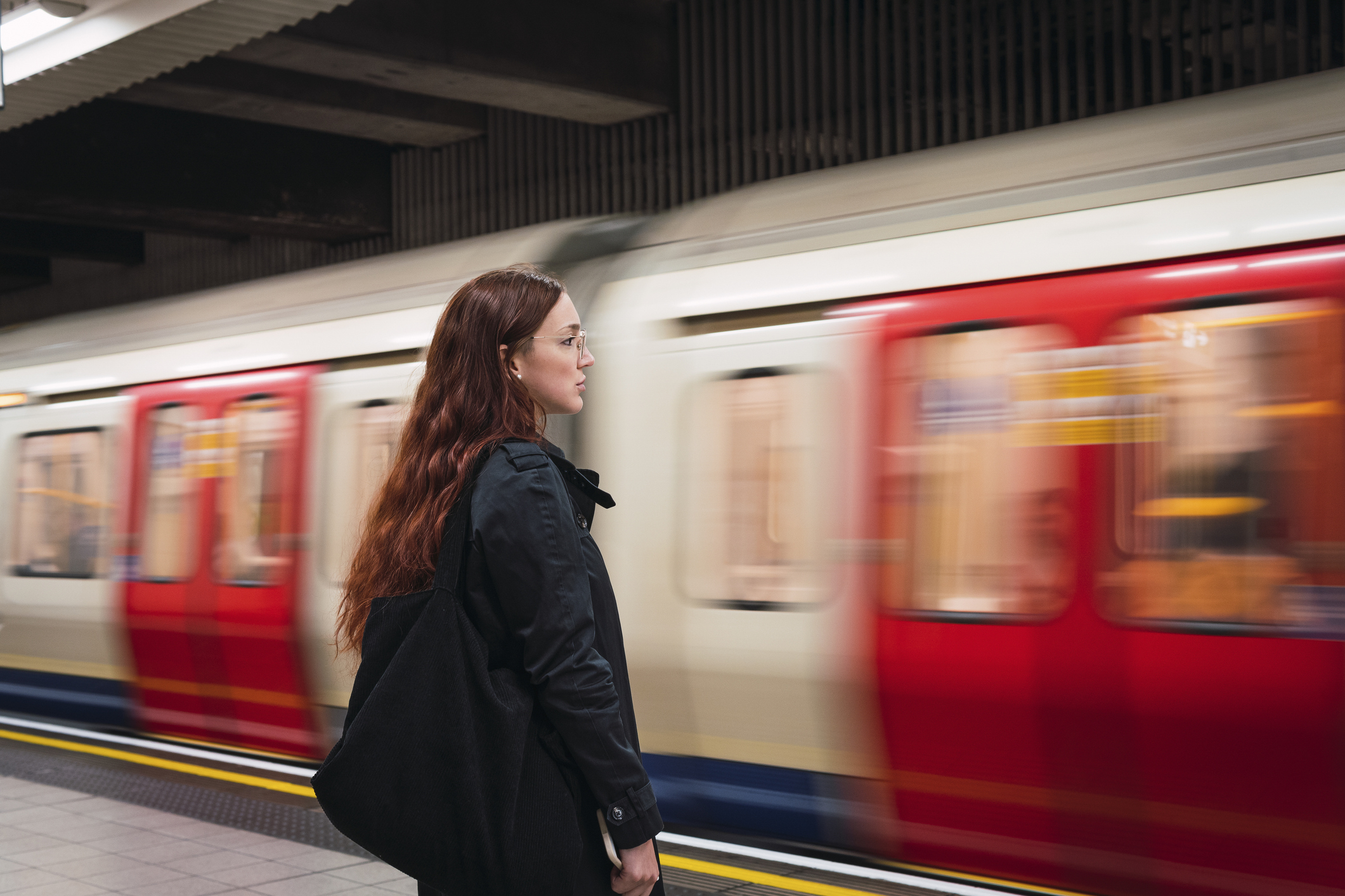 Woman standing on a platform as a blurred train passes by