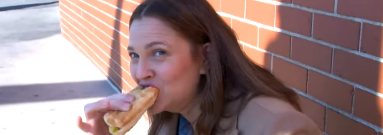 Drew Barrymore eating a Chicago style hot dog outside