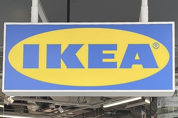 IKEAの看板が掲げられた店舗の入り口、周囲には買い物をする人々がいる。