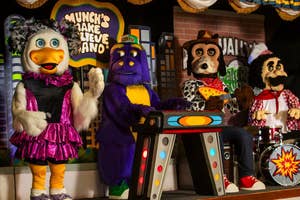Animated band characters from Chuck E. Cheese's performing on stage with instruments