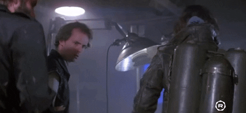 A scene from 'The Thing' showing Kurt Russell and two other characters in a tense moment with flamethrowers