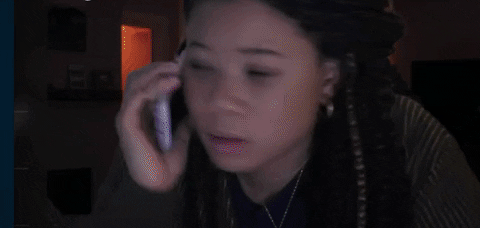 Woman on phone with concerned expression, in a dimly lit room