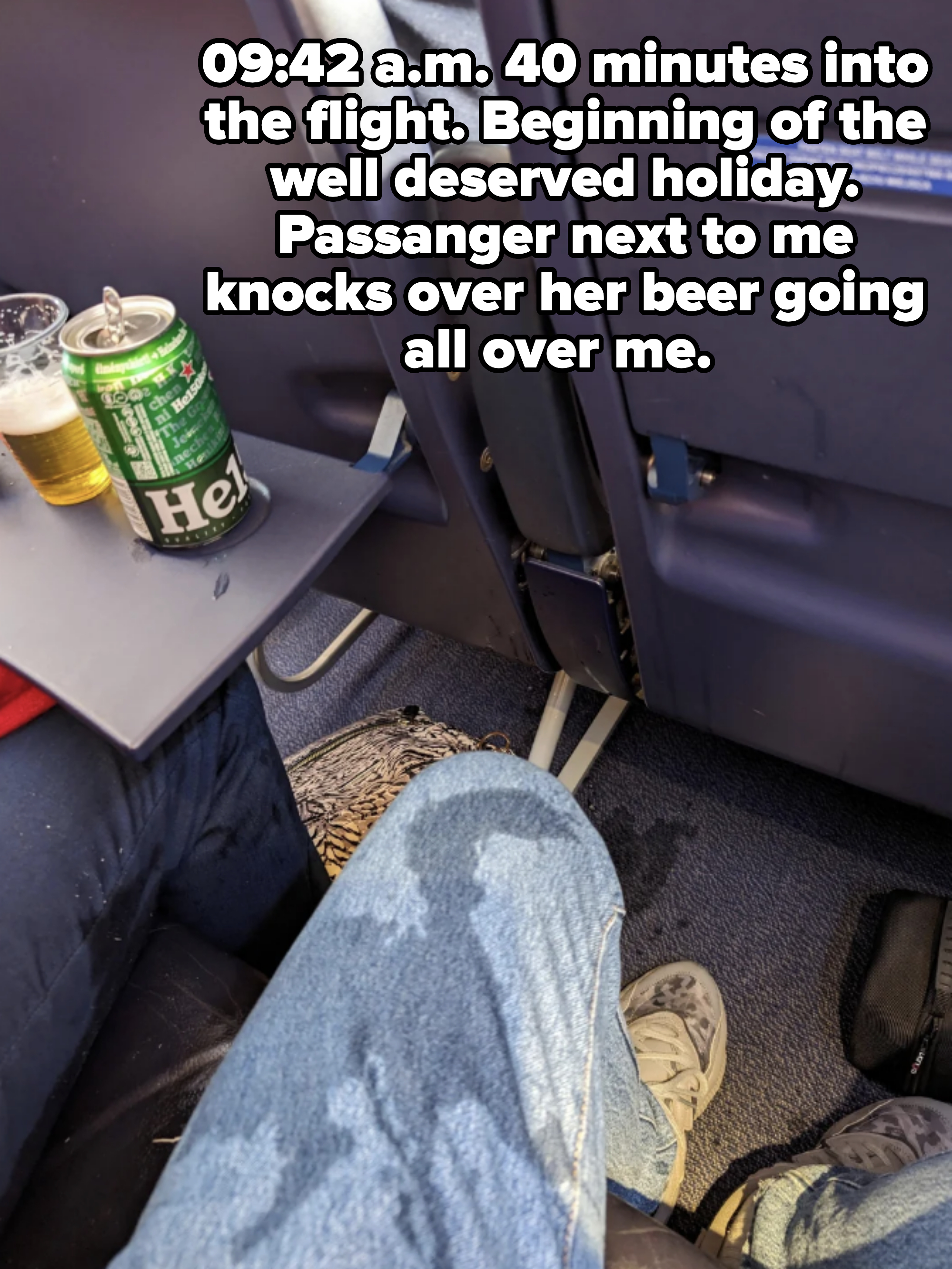 Passenger's legroom with an open beverage can on the tray table aboard an airplane