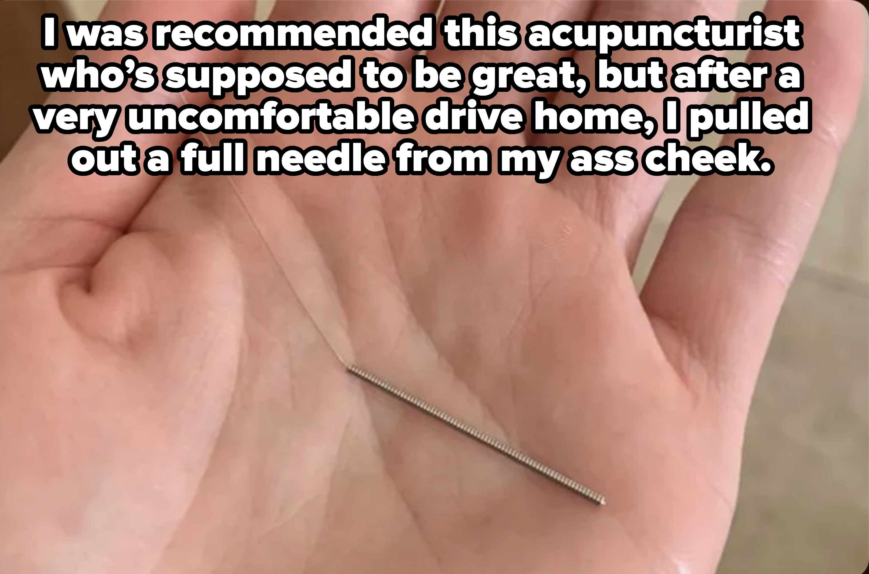 Hand holding a small metallic object, possibly a screw or pin