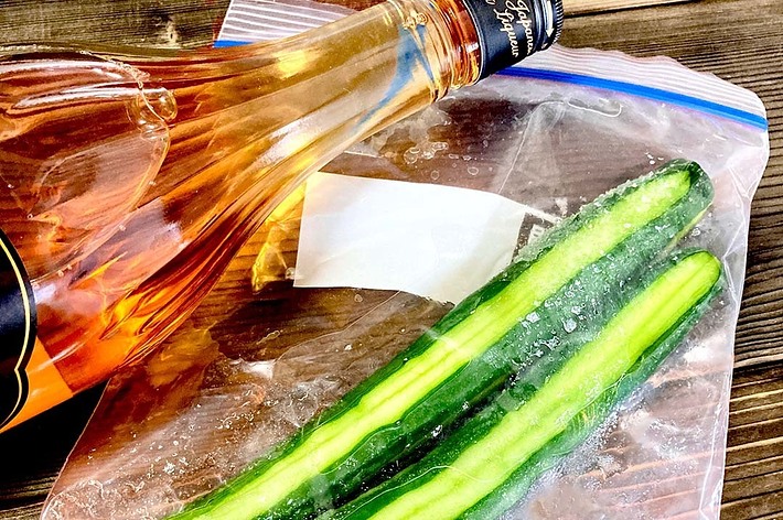 プラスチック袋に入ったきゅうり2本とその隣に置かれたウイスキーのボトル。