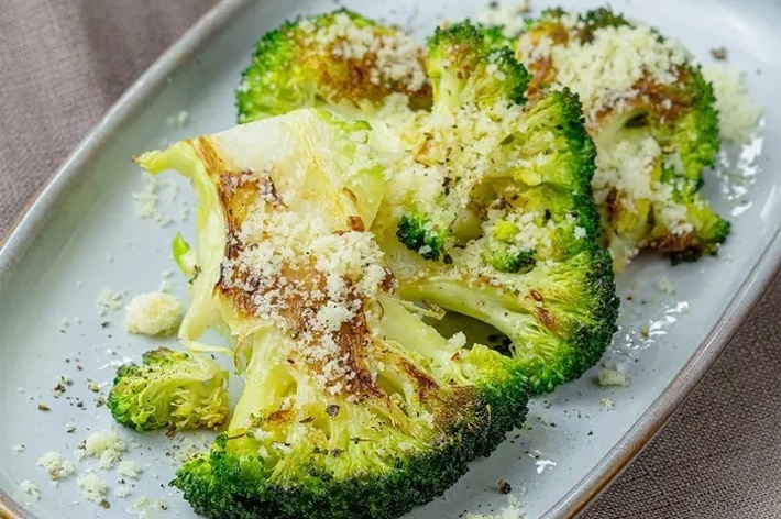 皿の上にパルメザンチーズを振りかけたローストブロッコリー。