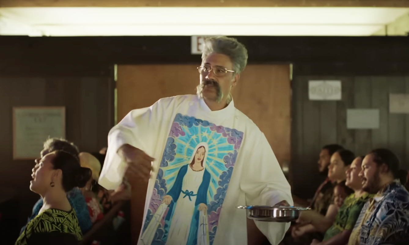 Person in a clergy robe with a religious figure print, holding a collection plate in a gathering