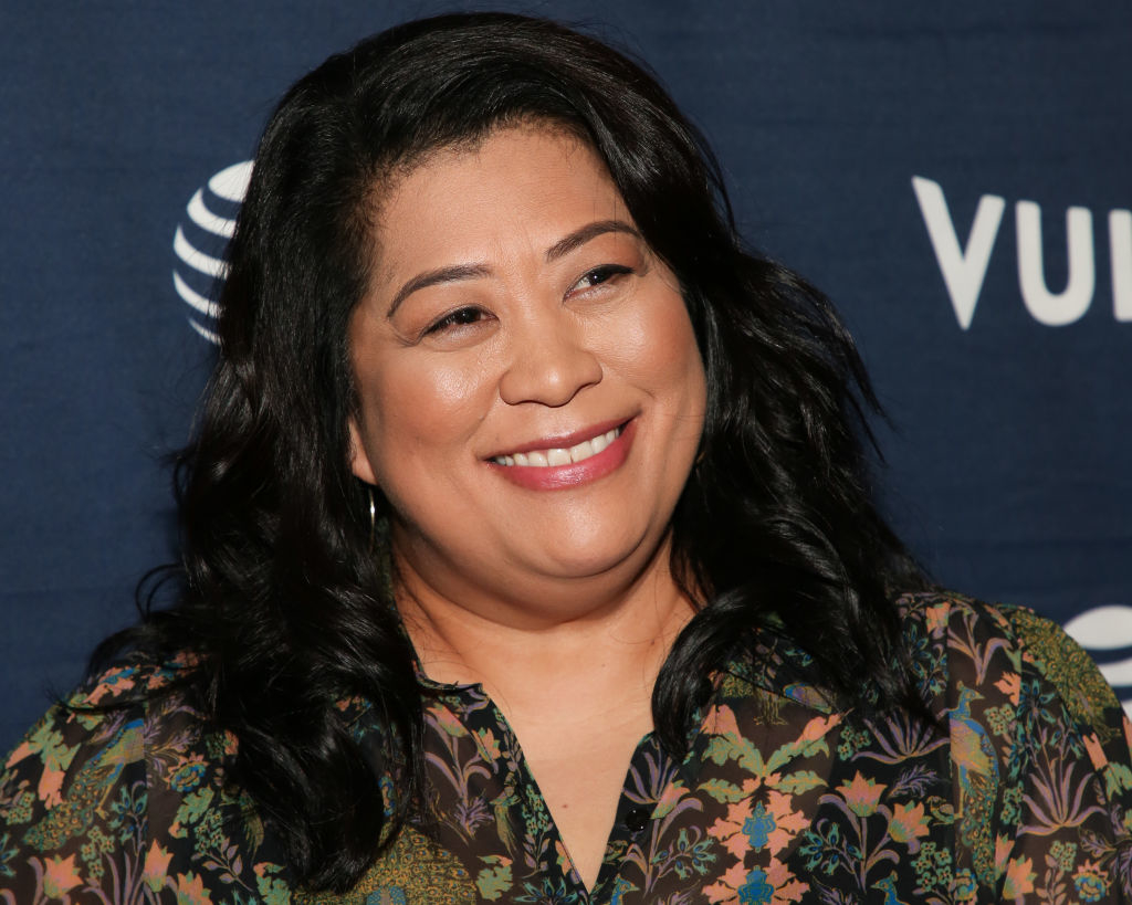 Woman with a patterned top smiling at a media event
