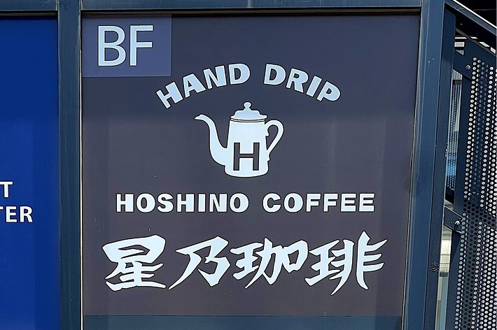 Sign for Hoshino Coffee advertising Hand Drip Coffee, with English and Japanese text, above a red panel