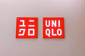 Two Uniqlo brand logos displayed side by side on a wall, one in Japanese and the other in English