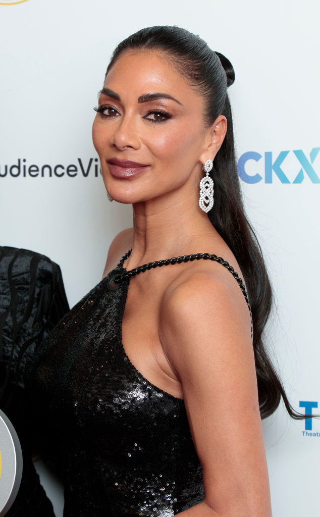 Woman in sequined dress with high bun and chandelier earrings on a celebrity event