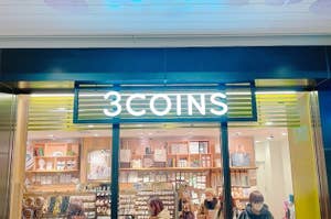 店舗の入り口に「3COINS」と書かれた看板、店内に商品が並ぶ様子と買い物をする人々。