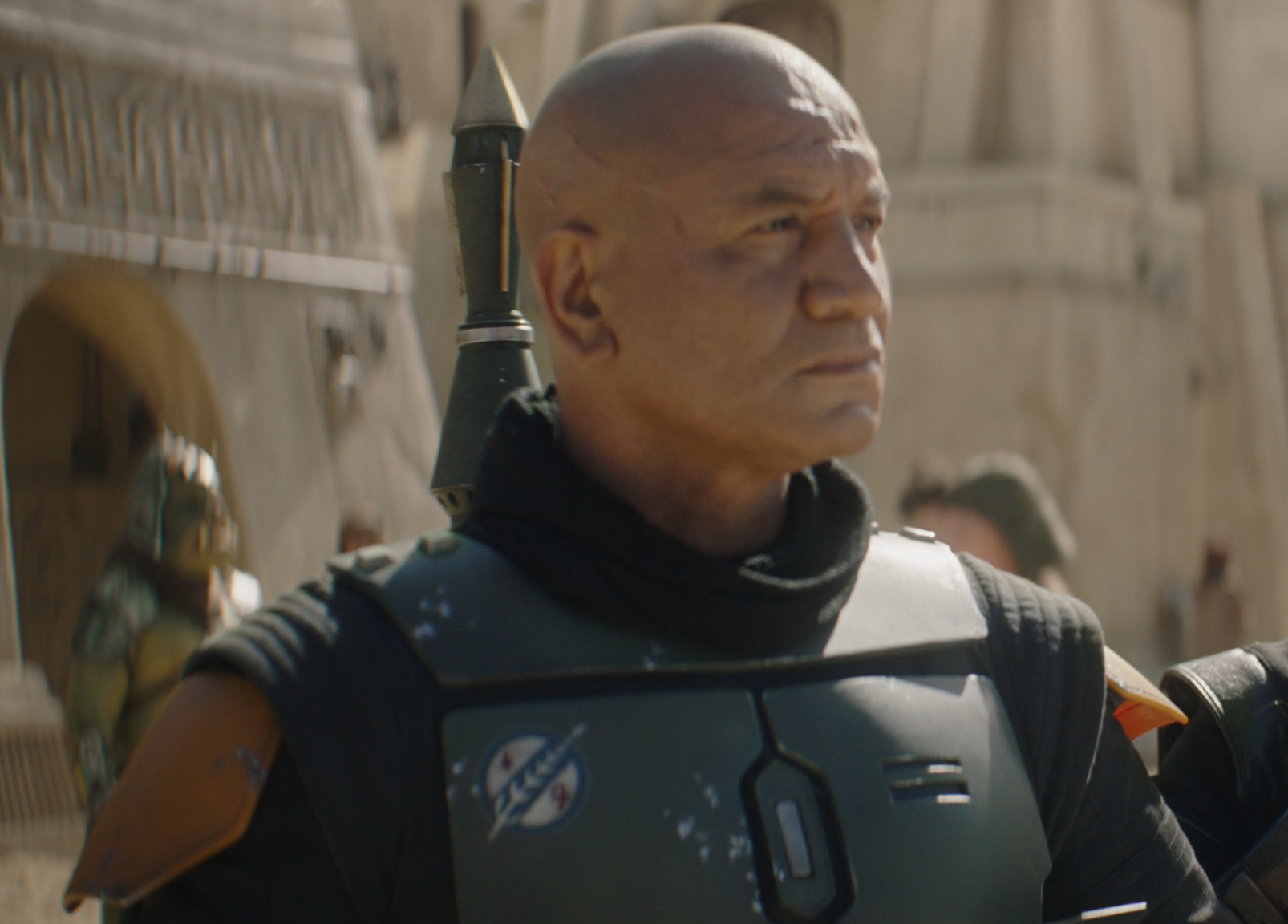 Character in futuristic armor with a rocket on the back, standing in a desert-like setting