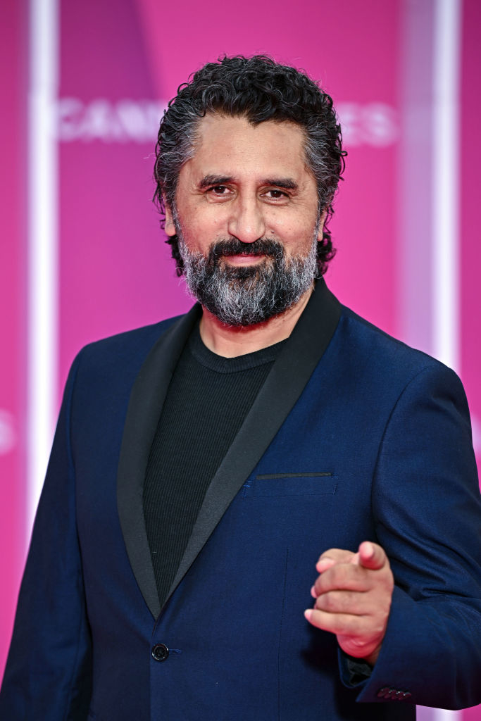 Man at event in a navy suit and black lapels, offering a handshake