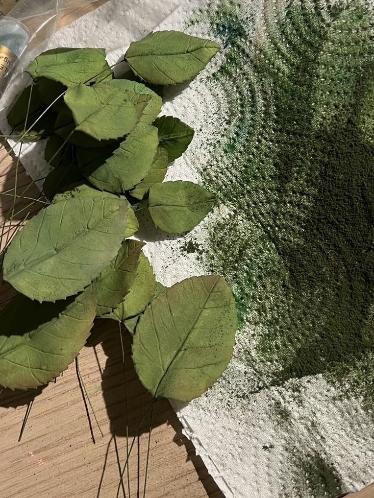 緑の葉っぱが散らばった刺しゅう作業中のキャンバス。