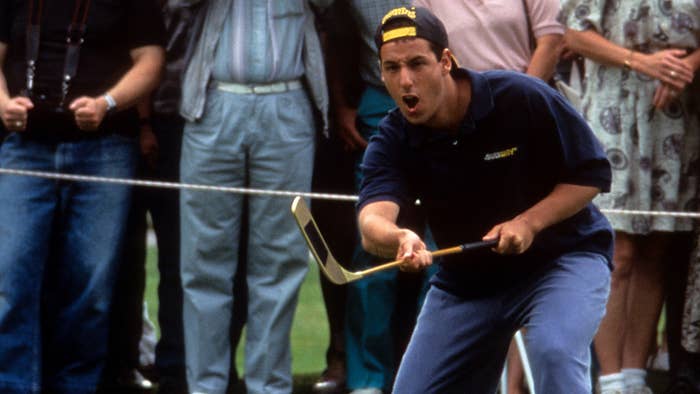 Adam Sandler in &#x27;Happy Gilmore&#x27; wearing a blue t-shirt and khakis, doing a hockey-style golf swing