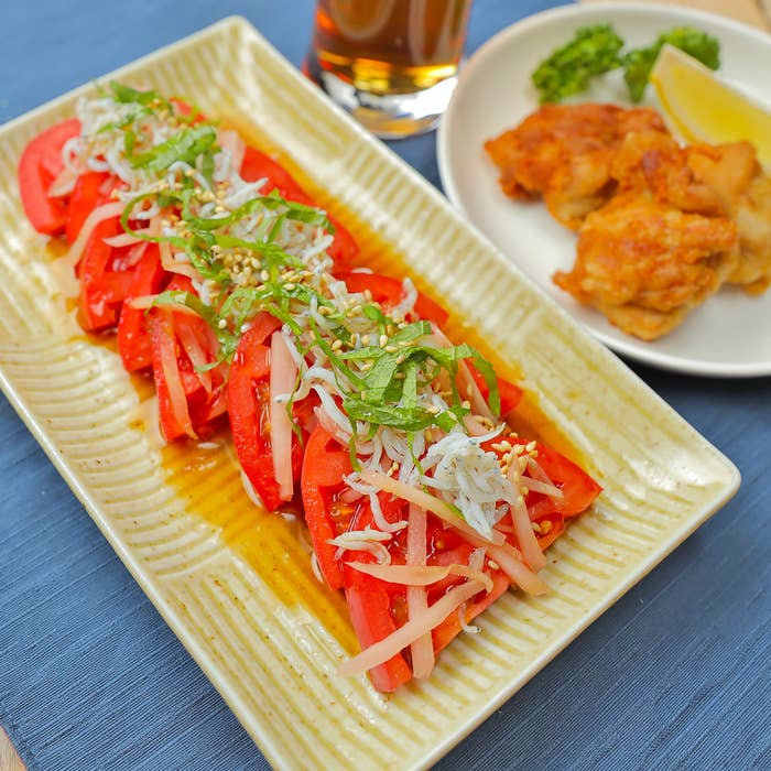 トマトにごまをトッピング。横にレモンと唐揚げが添えられています。