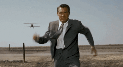 Man in a suit running towards the camera with an airplane in the background