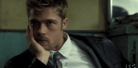 Brad Pitt posing with a hand on his cheek, looking pensive, wearing a suit and tie