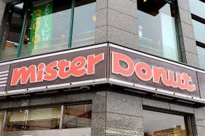 Exterior sign of Mister Donut shop with large storefront windows and reflections of the sky