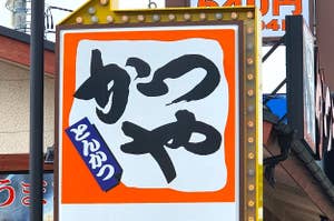 看板には大きな文字で「めん」と書かれ、下には駐車場を指す矢印があります。
