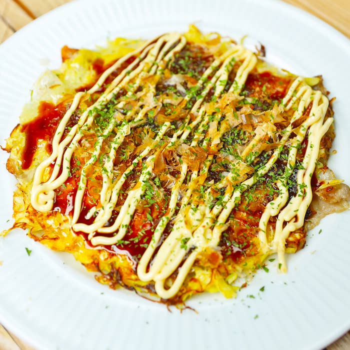 お好み焼きが白い皿に盛られている。ソースとマヨネーズがかかっている。