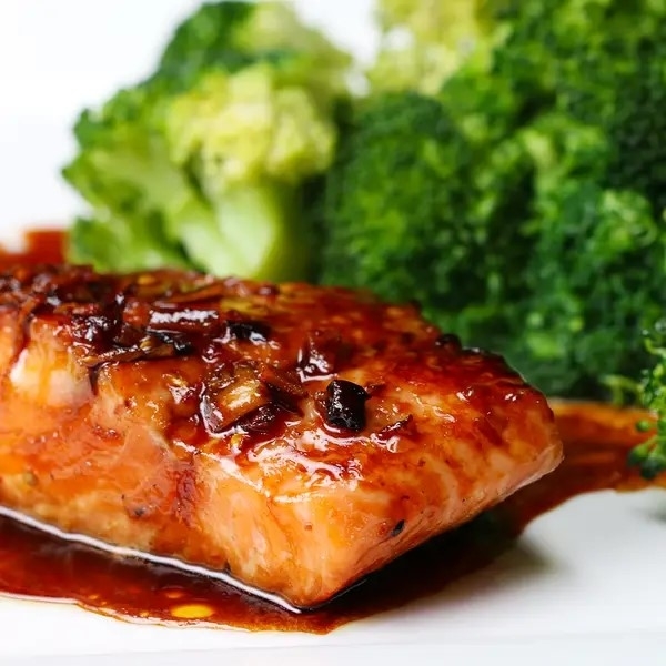 Grilled salmon with glaze alongside steamed broccoli