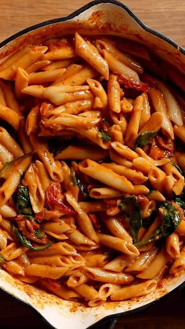 A pot of penne pasta with spinach and tomato sauce