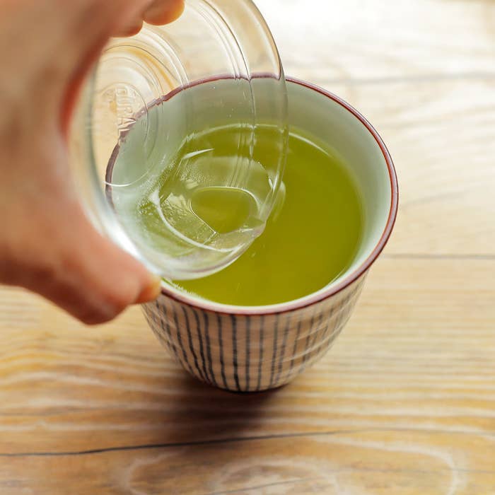 手がお茶を注いでいる茶碗を持っています。