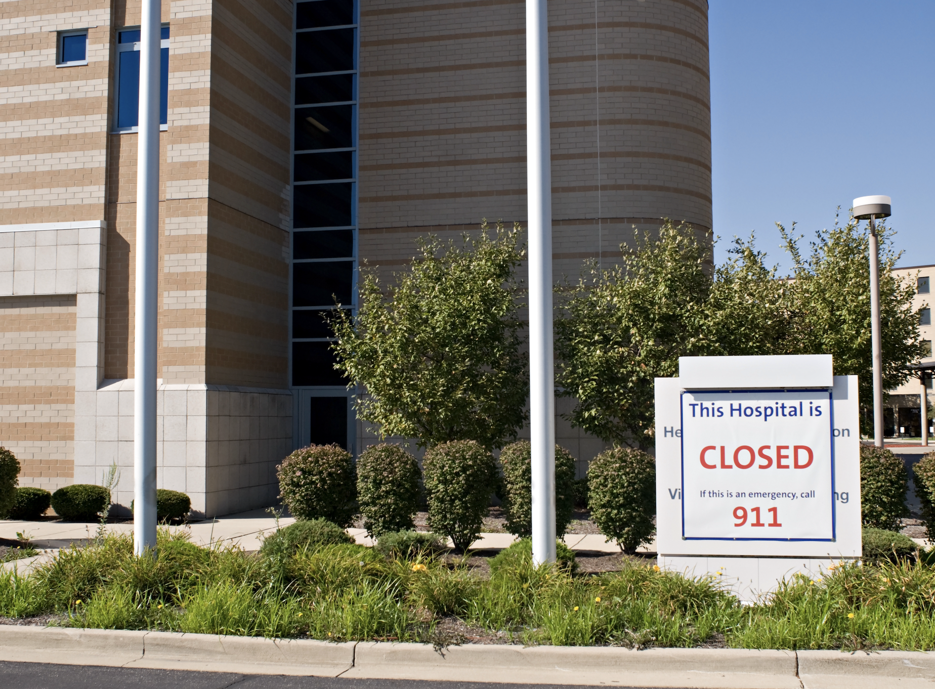 Sign in front of a hospital reads "This Hospital is CLOSED" and instructs to call 911 in emergencies