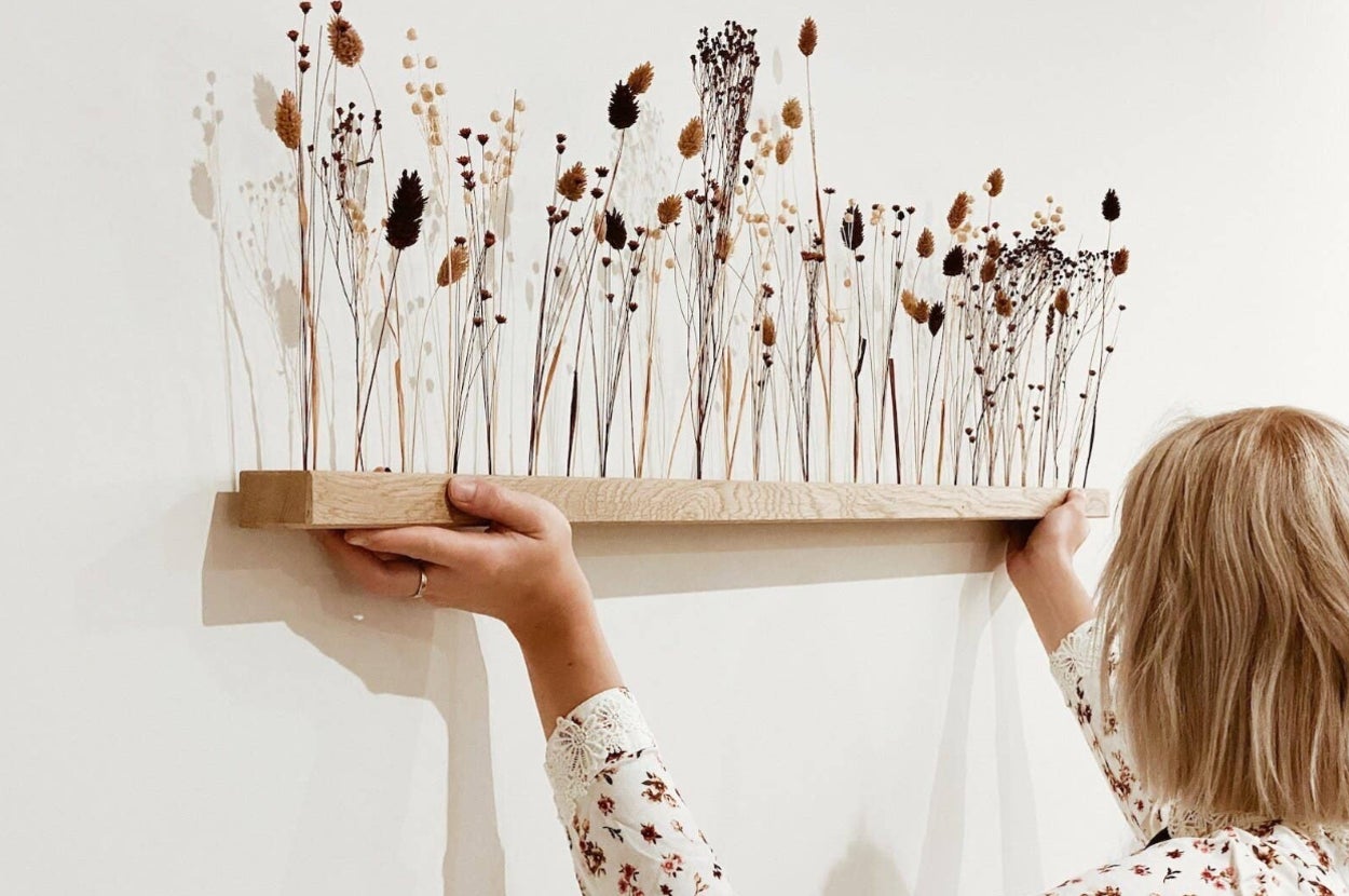 a wall art piece with dried flowers coming out of a wooden base