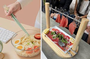 A person uses tongs to mix pasta in a bowl; a wooden stand holds slices of cured meat over a plate