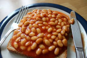 A plate of beans on toast with a fork and knife on either side