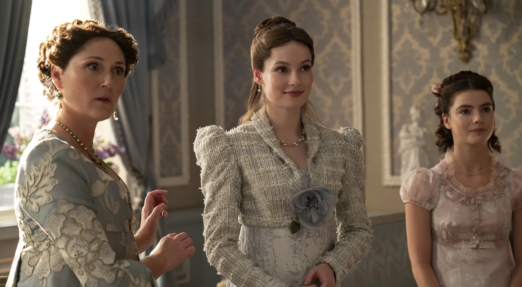 Tres personajes de época en vestidos clásicos con adornos, posan en una habitación elegante
