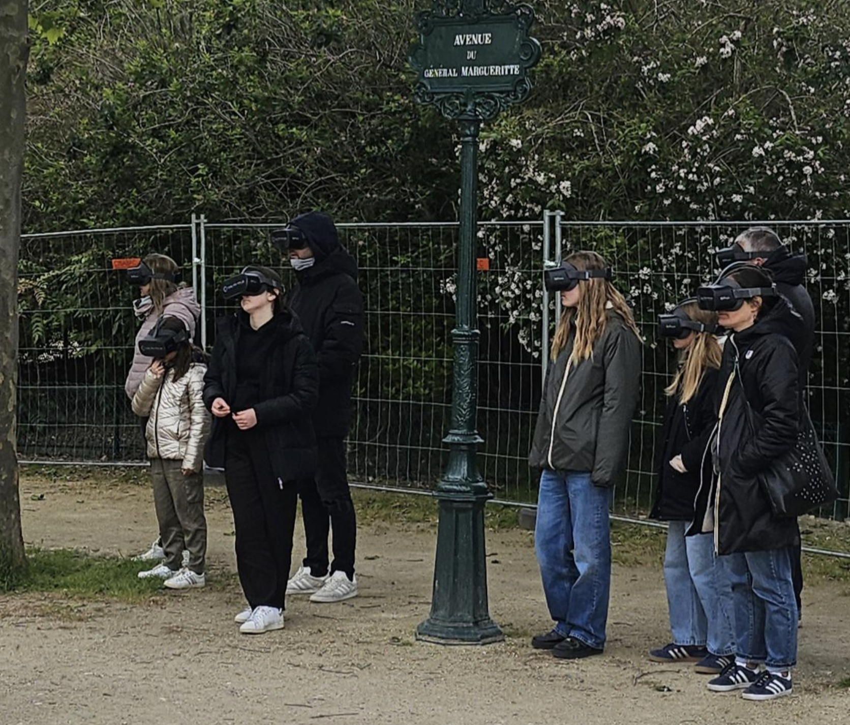 Group of people using VR headsets outdoors near a signpost