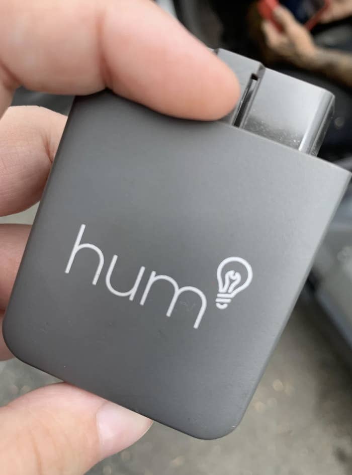 Hand holding a &#x27;hum&#x27; branded lighter with a lightbulb design next to the logo