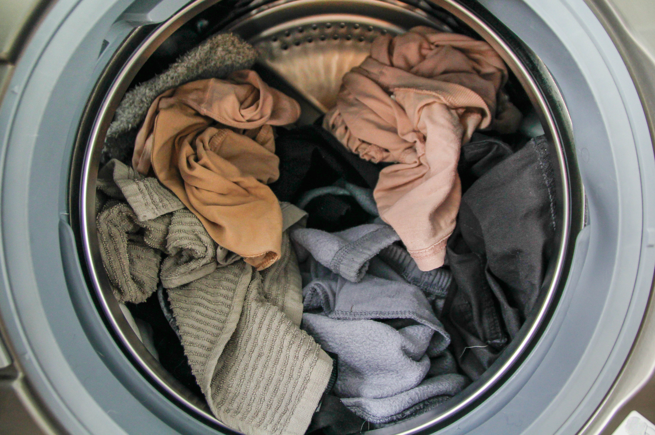 Open washing machine with a mix of laundry items inside