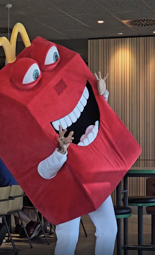 Person in a Happy Meal costume waving, inside a restaurant