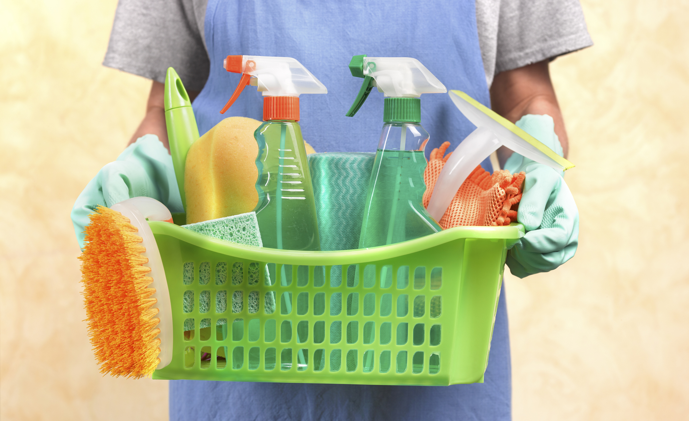 Person holding a basket with cleaning supplies, depicting household chores possibly related to cohabitation dynamics