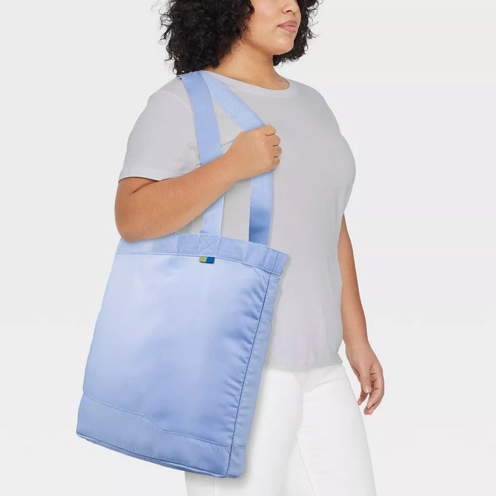 a model holding a large light blue tote bag on their shoulder